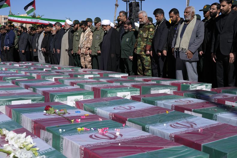 Varias personas rezan frente a los ataúdes de las víctimas de un ataque suicida durante su funeral en la ciudad de Kermán, Irán, el viernes 5 de enero de 2024. (AP Foto/Vahid Salemi)