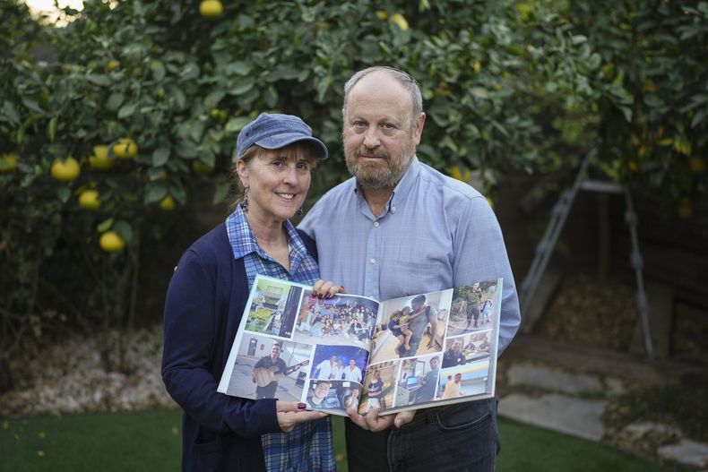 Hazel y David Brief sostienen un álbum de fotos hecho por su hijo Yona Brief, que murió 14 meses después de que milicianos de Hamás le dispararan 13 veces el 7 de octubre de 2024 en Kfar Aza, en su casa de Modiin, Israel, el 8 de diciembre de 2024. (AP foto/Sam McNeil)