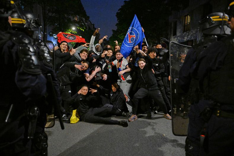 Hinchas del Paris Saint-Germain frente a policías al celebrar la victoria ante el Bayern Múnich en las semifinales de la Liga de Campeones, el jueves 7 de mayo de 2026, en París. (AP Foto/Emma Da Silva)