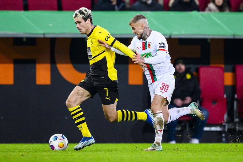 Gio Reyna del Borussia Dortmund y Niklas Dorsch del Augsburg en acción en el encuentro de la Bundesliga en Augsburg, Alemania el sábado 16 de diciembre del 2023. (Tom Weller/dpa via AP)