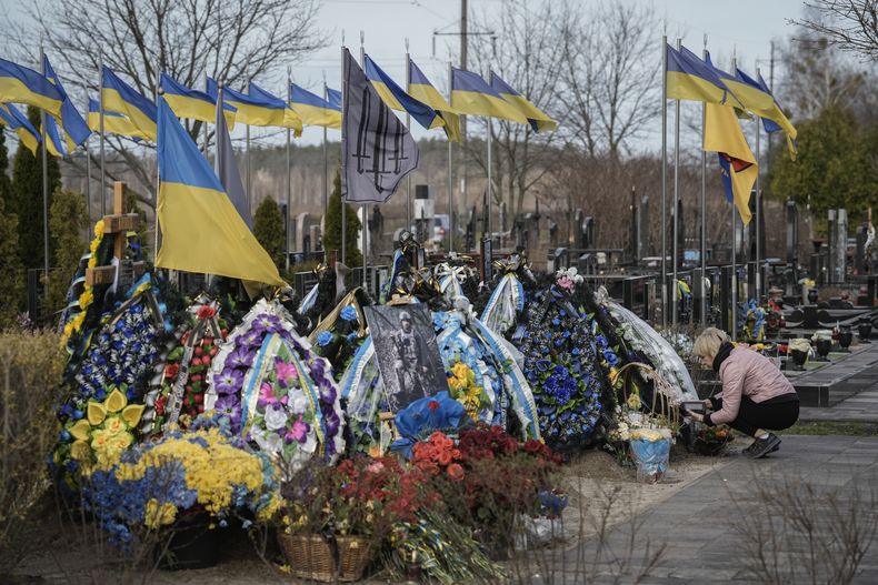 Una mujer limpia la tumba de un familiar muerto en combate, en el cementerio de Bucha, en las afueras de Kiev, el sábado 30 de marzo de 2024. (AP Foto/Enric Marti)