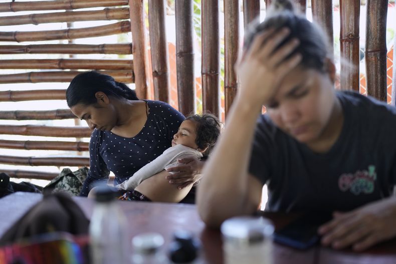 La migrante venezolana Gabriela Villanueva sostiene a su hija en Chepo, Panamá, el sábado 22 de febrero de 2025, durante una escala en su viaje desde el sur de México hasta Puerto de Cartí, en la costa caribeña de Panamá, en busca de un barco hacia Colombia, desde donde regresará a Venezuela. (Foto AP/Matías Delacroix)
