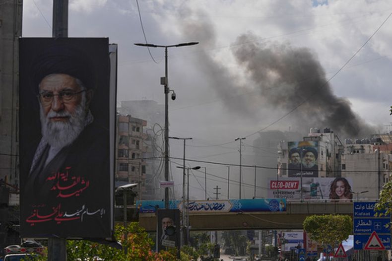 Vista de un retrato del difunto líder supremo de Irán, el ayatolá Ali Jamenei, y al fondo humo tras un ataque aéreo israelí en Dahiyeh, Beirut, Líbano, el 30 de marzo de 2026. (Foto AP/Hassan Ammar)