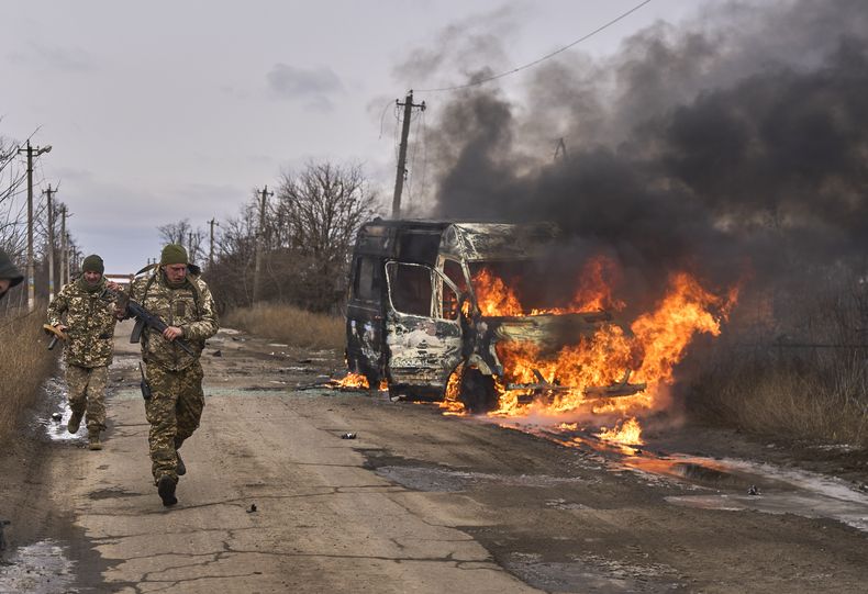 En esta foto distribuida por la 10ma Brigada de Montaña Edelweiss, de Ucrania, soldados ucranianos pasan junto a un bus impactado por un dron ruso cerca de Bajmut, región de Donetsk, Ucrania, 23 de noviembre de 2023. (Shandyba Mykyta, 10ma Brigada de Montaña Edelweiss, via AP)