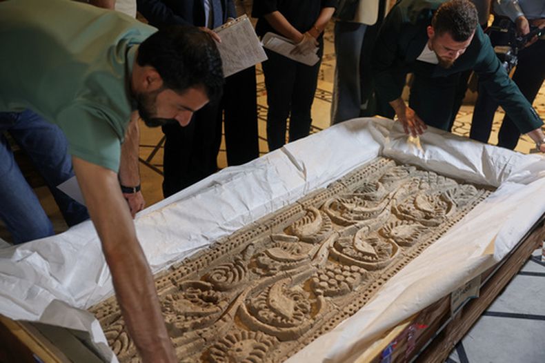 Varios empleados desempacan un panel de piedra labrada después de que autoridades sirias revelaran las antigüedades devueltas por Francia, en el Museo Nacional en Damasco, Siria, el miércoles 8 de julio de 2026. (AP Foto/Ghaith Alsayed)