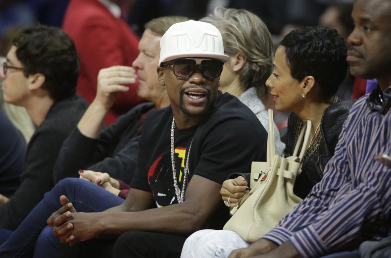 El boxeador Floyd Mayweather Jr., centro, habla con una persona no identificada durante un partido de b&aacute;squetbol el lunes, 8 de diciembre de 2014, en Los Angeles. (AP Photo/Jae C. Hong)