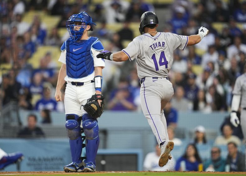 Ezequiel Tovar (14), de los Rockies de Colorado, anota en un sencillo de Kris Bryant en el tercer inning del juego de la MLB que enfrentó a su equipo con los Dodgers de Los Ángeles, en Los Ángeles, el 31 de mayo de 2024. (AP Foto/Ashley Landis)