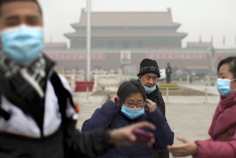 Turistas se colocan m&aacute;scaras luego de posar para tomarse fotograf&iacute;as en la plaza Tiananmen en un d&iacute;a donde hubo gran contaminaci&oacute;n en Beijing el martes 25 de febrero de 2014.  (Foto de AP/Alexander F. Yuan)