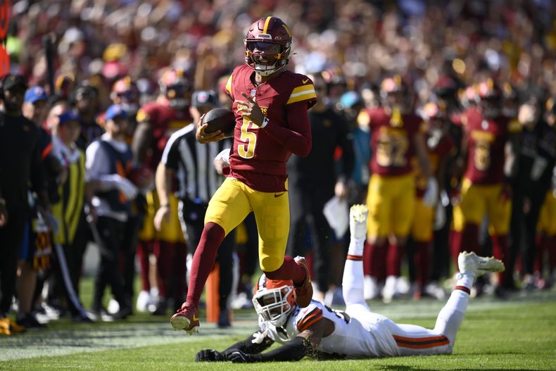 Jayden Daniels (5), quarterback de los Commanders de Washington, corre con el balón dejando atrás al defensive end Ogbo Okoronkwo (54), de los Browns de Cleveland, durante la primera mitad del juego de la NFL en Landover, Maryland, el domingo 6 de octubre de 2024. (AP Foto/Nick Wass)