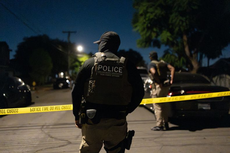 Un agente del grupo de trabajo de Investigaciones de Seguridad Nacional cerca de un cordón policial que delimita el perímetro durante un operativo federal contra un sospechoso de registrarse ilegalmente para votar, el lunes 19 de octubre de 2026, en Commerce, California. (AP Foto/Jae C. Hong)