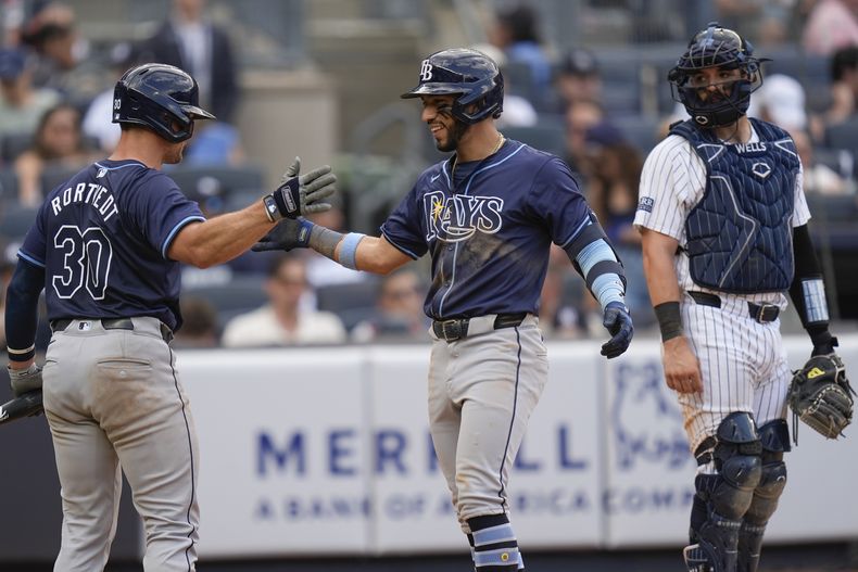 El panameño de los Rays de Tampa Bay, José Caballero (centro) celebra su cuadrangular con Ben Rortvedt (izquierda), ante la mirada del receptor de los Yankees de Nueva York, Austin Wells (derecha), durante el noveno episodio del juego de béisbol en el Yankee Stadium, el 21 de julio de 2024, en Nueva York. (AP Foto/Seth Wenig)