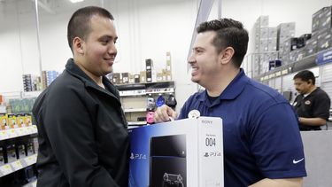 americateve | Andy Varadez (izquierda) recibe una consola PlayStation 4 de manos del gerente de Best Buy Michael Centeno luego de comprar el producto en la tienda de Best Buy en Lincoln Park, Chicago, el viernes 15 de noviembre de 2013. (Foto AP/Nam Y. Huh)