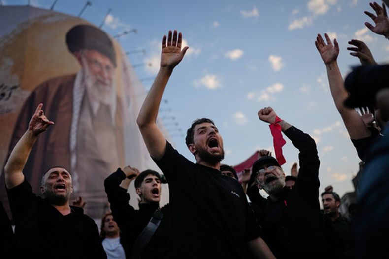 Un grupo de personas lanza consignas al congregarse en la plaza de la Revolución Islámica para la procesión fúnebre del fallecido líder supremo de Irán, el ayatolá Alí Jamenei, bajo una valla publicitaria que muestra la imagen de Jamenei, en Teherán, Irán, el lunes 6 de julio de 2026. (Foto AP/Altaf Qadri)