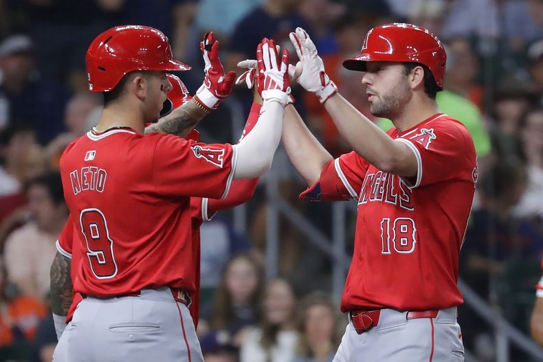Zach Neto (9), Willie Calhoun, atrás, y Nolan Schanuel (18), de los Angelinos de Los Ángeles, celebran en el plato después de anotar con cuadrangular de tres carreras de Schanuel en contra de los Astros de Houston durante la quinta entrada del juego de béisbol el lunes 20 de mayo de 2024, en Houston. (AP Foto/Michael Wyke)