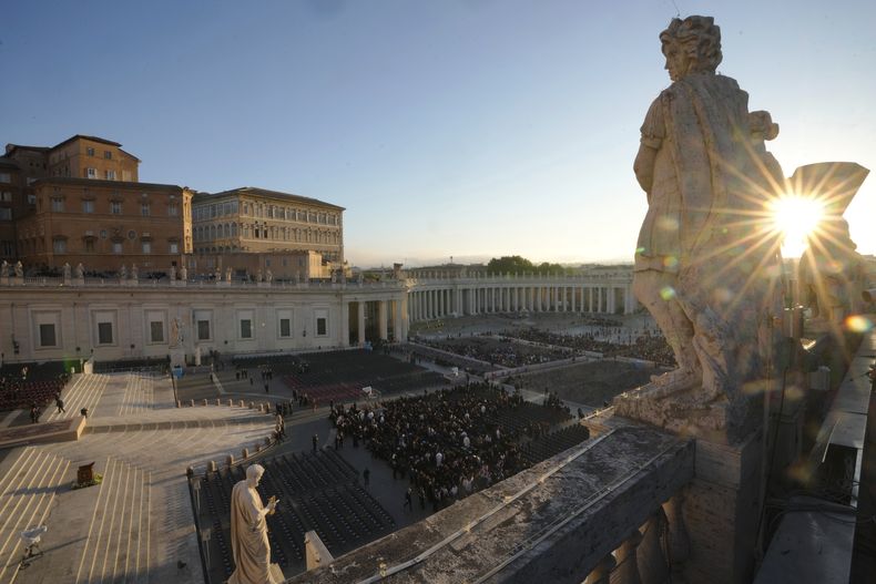Los primeros rayos de sol de la mañana se cuelan a través de una estatua mientras los asistentes empiezan a tomar asiento antes del funeral del papa Francisco, en la Plaza de San Pedro del Vaticano, el 26 de abril de 2025. (AP Foto/Markus Schreiber)