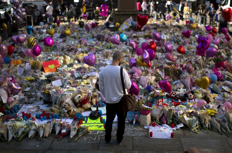 Un hombre observa flores y globos colocados en honor de las víctimas de un ataque con bomba en un concierto de Ariana Grande, el 26 de mayo de 2017, en la Plaza St. Ann, en el centro de Manchester, Inglaterra. (AP Foto/Emilio Morenatti, Archivo)