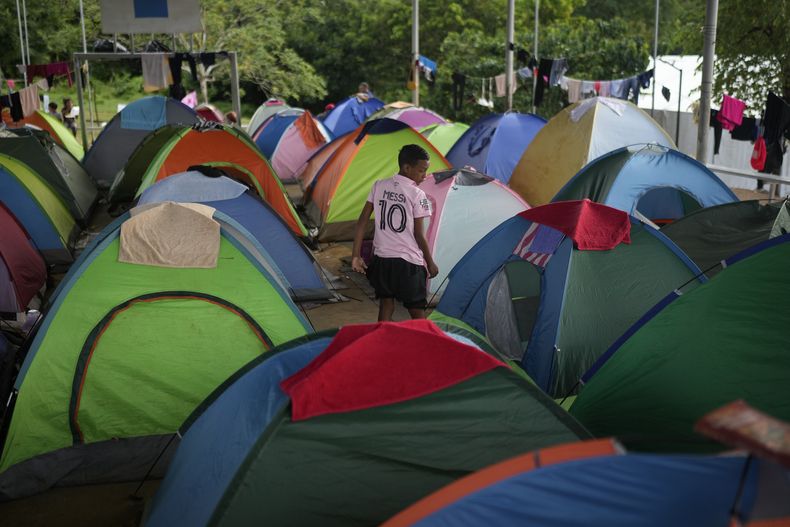 ARCHIVO - Un migrante que cruzó a pie el Tapón del Darién desde Colombia, camina entre tiendas de campaña en un campamento temporal en Lajas Blancas, Panamá, el 28 de junio de 2024. El número de niños y adolescentes que cruzan sin acompañantes la frontera entre Panamá y Colombia a través de la peligrosa selva de Darién creció en un 35% hasta noviembre de 2024, de acuerdo con la información divulgada por Unicef el miércoles 18 de diciembre de 2024. (Foto AP/Matias Delacroix, Archivo)