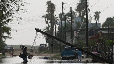 Un hombre transporta objetos a través de aguas inundadas, pasando junto a líneas eléctricas derribadas tras el paso del huracán Polo en Puerto San Carlos, estado de Baja California Sur, México, el martes 29 de septiembre de 2026. (Foto AP/Eduardo Verdugo)