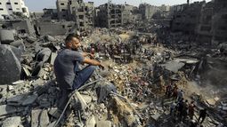 Un hombre se sienta sobre los escombros mientras otros buscan entre los restos de edificios atacados por la aviación israelí, en el campo de refugiados de Jabaliya, en el norte de la Franja de Gaza, el 1 de noviembre de 2023. (AP Foto/Abed Khaled)