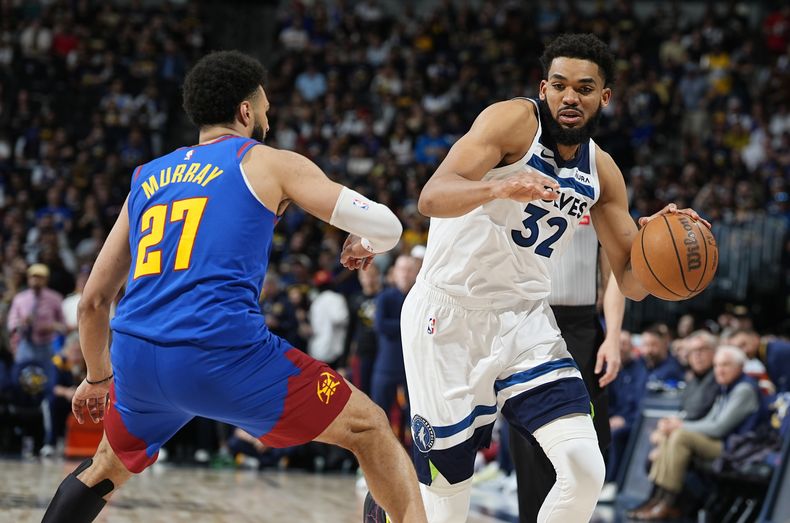 El pívot de los Timberwolves de Minnesota, Karl-Anthony Towns, a la derecha, supera al escolta de los Nuggets de Denver, Jamal Murray, a la izquierda, en la segunda mitad del Juego 1 de una serie de playoffs de segunda ronda de baloncesto de la NBA, el sábado 4 de mayo de 2024, en Denver. (AP Foto/David Zalubowski)