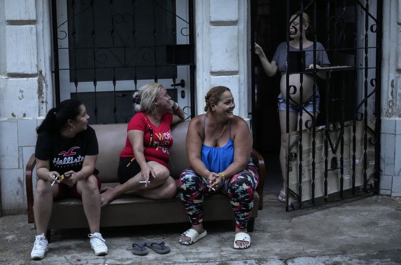 Varias mujeres pasan el tiempo fuera de casa durante el apagón masivo en el que derivó la caída en el funcionamiento de una de las mayores plantas termoeléctricas del país, en La Habana, Cuba, el viernes 18 de octubre de 2024. (AP Foto/Ramón Espinosa)