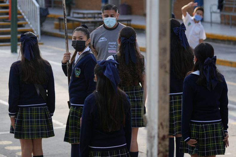 Estudiantes y maestros de escuelas públicas usan mascarillas faciales obligatorias en medio de un brote de sarampión, durante una ceremonia en su escuela en Guadalajara, México, el jueves 5 de febrero de 2026. (AP Foto/Fernando Llano)