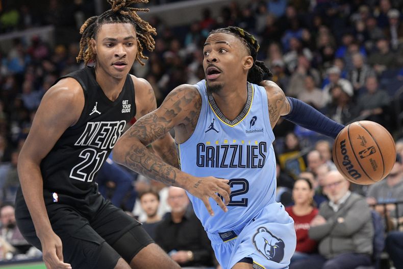 Ja Morant (12), de los Grizzlies de Memphis, avanza con el balón frente a Noah Clowney (21), de los Nets de Brooklyn, en la primera mitad del juego de baloncesto de la NBA, el viernes 13 de diciembre de 2024, en Memphis, Tennessee. (AP Foto/Brandon Dill)