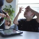 Charlie Lamb (der), quien ha sido diagnosticado con autismo y es no-verbal, usa un dispositivo para comunicarse con su madre Eileen Lamb (izq), quien también tiene autismo, junto con su hermana Billie, en Austin, Texas, el 12 de mayo del 2025. (AP foto/Eric Gay)