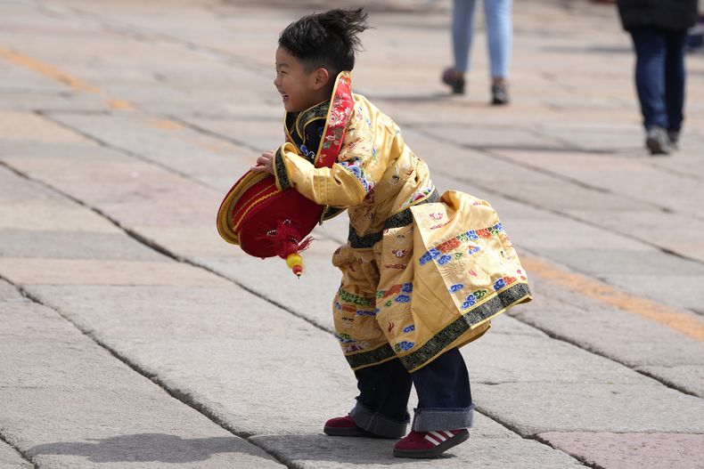 Un niño vestido de emperador reacciona tras recuperar la corona que le arrancó una ráfaga de viento, en el exterior de la Ciudad Prohibida, Beijing, China, el 12 de abril de 2025. (AP Foto/Ng Han Guan)
