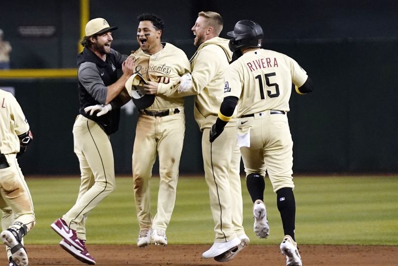 Gabriel Moreno (centro), de los Diamondbacks de Arizona, festeja tras conectar el sencillo de la victoria sobre los Cachorros de Chicago, el sábado 16 de septiembre de 2023 (AP Foto/Ross D. Franklin)