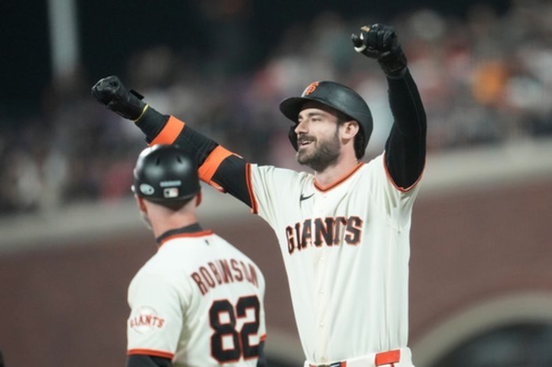 Bryce Eldridge de los Gigantes de San Francisco hace un gesto junto al coach de primera base Shane Robinson tras batear un sencillo remolcador en la octava del segundo juego de la doble cartelera ante los Diamondbacks de Arizona. (AP Foto/Jeff Chiu)