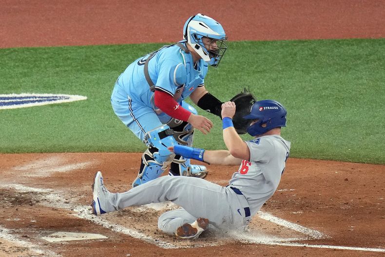 Will Smith, de los Dodgers de Los Ángeles, anota frente al mexicano Alejandro Kirk, catcher de los Azulejos de Toronto, en el sexto juego de la Serie Mundial, el viernes 31 de octubre de 2025 (Chris Young/The Canadian Press via AP)