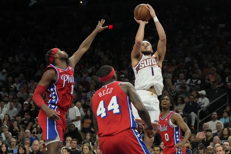El base de los Suns de Phoenix Devin Booker lanza el balón entre el base de los 76ers de Filadelfia Buddy Hield y el base Tyrese Maxey el miércoles 20 de marzo del 2024. (AP Foto/Rick Scuteri)