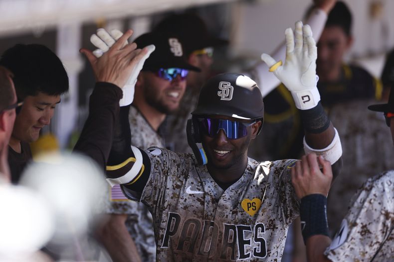 Jurickson Profar, centro, de los Padres de San Diego, es felicitado en el dugout después de conectar un jonrón solitario contra los Medias Blancas de Chicago en la tercera entrada el domingo 22 de septiembre de 2024 en San Diego. (AP Foto/Derrick Tuskan)