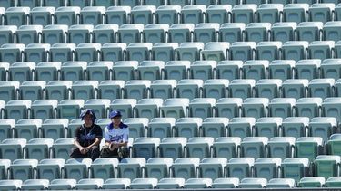 Aficionados de los Dodgers de Los Ángeles observan desde asientos vacíos mientras se protegen del sol y el calor antes del primer juego de una serie divisional de los playoffs de la Liga Nacional de béisbol contra los Bravos de Atlanta, el 3 de octubre de 2026, en Los Ángeles. (Foto AP/Jae C. Hong)