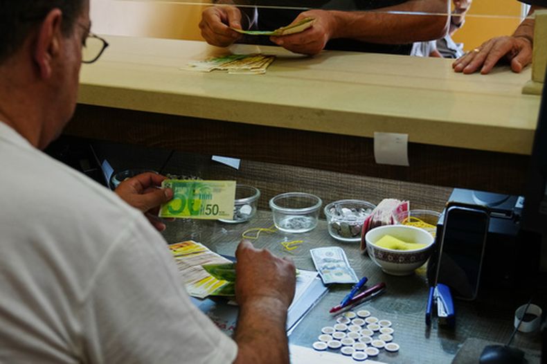 Un empleado de una casa de cambio cuenta shekels israelíes en una oficina en Belén, Cisjordania, el martes 7 de julio de 2026. (AP Foto/Mahmoud Illean)
