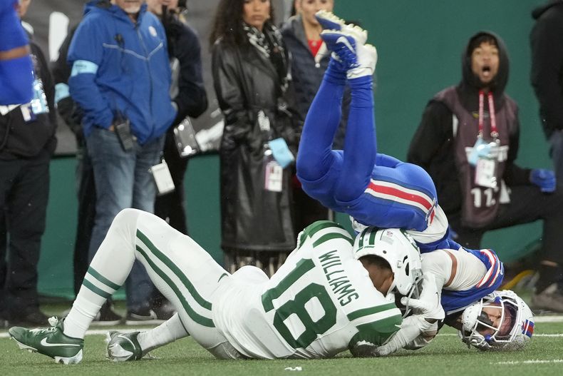 Taron Johnson, derecha, corner de los Bills de Buffalo, intercepta un pase que buscaba las manos de Mike Williams (18), wide receiver de los Jets de Nueva York, durante la segunda mitad del partido de la NFL del lunes 14 de octubre de 2024, en East Rutherford, Nueva Jersey. (AP Foto/Pamela Smith)