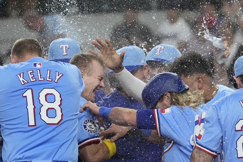 Josh Jung, segundo desde la izquierda, de los Rangers de Texas, celebra con Carson Kelly (18) y sus demás compañeros después de disparar jonrón de tres carreras en la 10ma entrada del juego de béisbol en contra de los Atléticos de Oakland, el domingo 1 de septiembre de 2024, en Arlington, Texas. (AP Foto/LM Otero)
