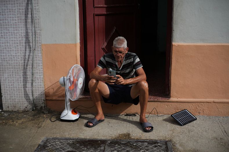Un hombre carga su ventilador y su teléfono celular con un panel solar durante un apagón en La Habana, el 17 de marzo del 2026. (AP foto/Ramón Espinosa)