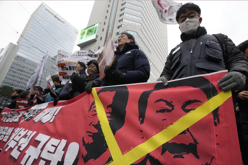 Manifestantes sostienen una pancarta con imágenes del presidente destituido Yoon Suk Yeol, a la derecha, y del presidente en funciones Han Duck-soo durante una concentración para exigir la detención de Yoon en Seúl, Corea del Sur, el sábado 21 de diciembre de 2024. (AP foto/Ahn Young-joon)