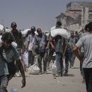 Palestinos cargan sacos de harina descargados por un convoy de ayuda humanitaria que llegó a Ciudad de Gaza desde el norte de la Franja de Gaza, el domingo 27 de julio de 2025. (AP Foto/Abdel Kareem Hana)