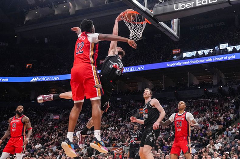 Sandro Mamukelashvili, centro derecha, de los Raptors de Toronto, retaca el balón frente a Derik Queen (22), de los Pelicans de Nueva Orleans, durante la primera mitad del juego de baloncesto de la NBA, el viernes 27 de marzo de 2026, en Toronto. (Chris Young/The Canadian Press via AP)