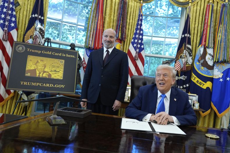 El presidente Donald Trump acompañado del secretario de Comercio, Howard Lutnick, quien se encuentra de pie a un costado de un cartel de la Tarjeta Dorada Trump en el Despacho Oval de la Casa Blanca, el viernes 19 de septiembre de 2025, en Washington. (AP Foto/Alex Brandon)