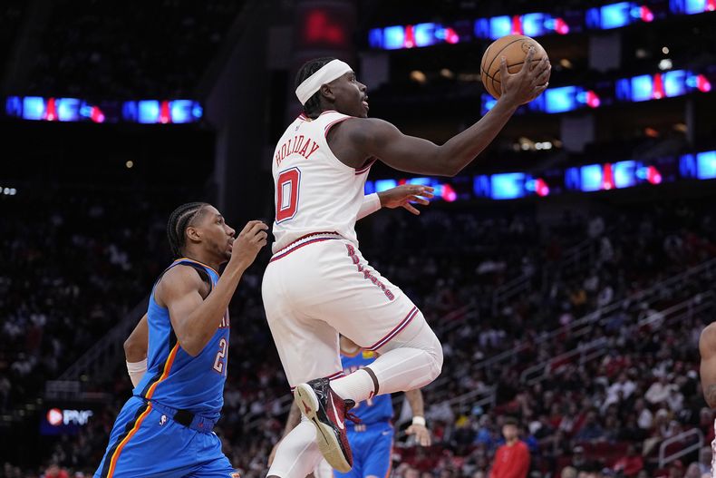 El base de los Rockets de Houston Aaron Holiday salta con el balón superando al base del Thunder de Oklahoma City Aaron Wiggins en el encuentro de la NBA el miércoles 6 de diciembre del 2023. (AP Foto/Kevin M. Cox)