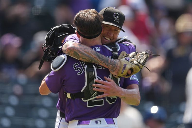 Kyle Freeland, derecha, abridor de los Rockies de Colorado, abraza al receptor Brett Sullivan, después de que forzara a un out con un elevado a Tyler Tolbert para terminar el juego con al lanzar la ruta completa, en el juego de béisbol de Grandes Ligas del domingo 2 de agosto de 2026, en Denver. (AP Foto/David Zalubowski)