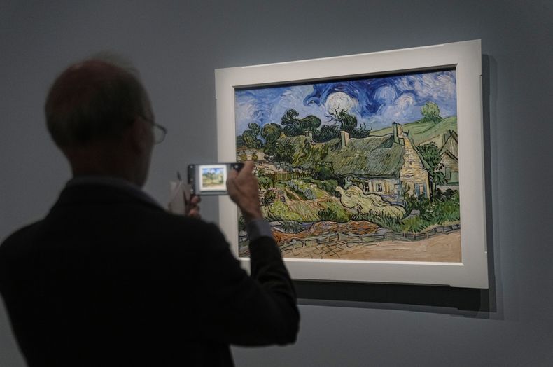 Un hombre fotografía el óleo sobre lienzo de Vincent Van Gogh Cabañas con techo de paja de Cordeville en Auvers-sur-Oise, (1890), en la exposición Van Gogh en Auvers-sur-Oise: Los últimos meses en el Museo de Orsay en París, viernes 29 de septiembre de 2023. La exposición se abre al público del 3 de octubre de 2023 al 4 de febrero de 2024 y se centra en los dos meses previos a su muerte a los 37 años el 29 de julio de 1890. (Foto AP/Michel Euler)