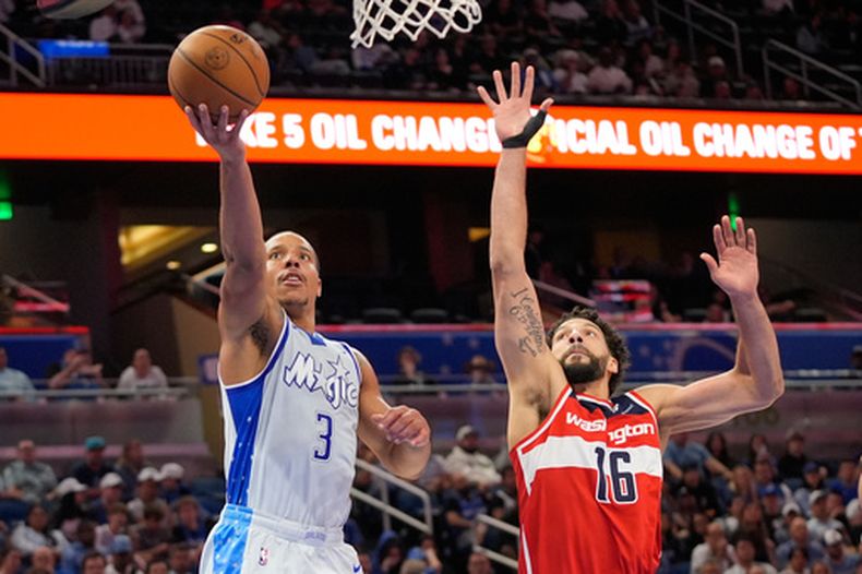 El base del Magic de Orlando Desmond Bane salta para anotar mientras lo defiende el alero de los Wizards de Washington Anthony Gill en el encuentro del jueves 12 de marzo del 2026. (AP Foto/John Raoux)