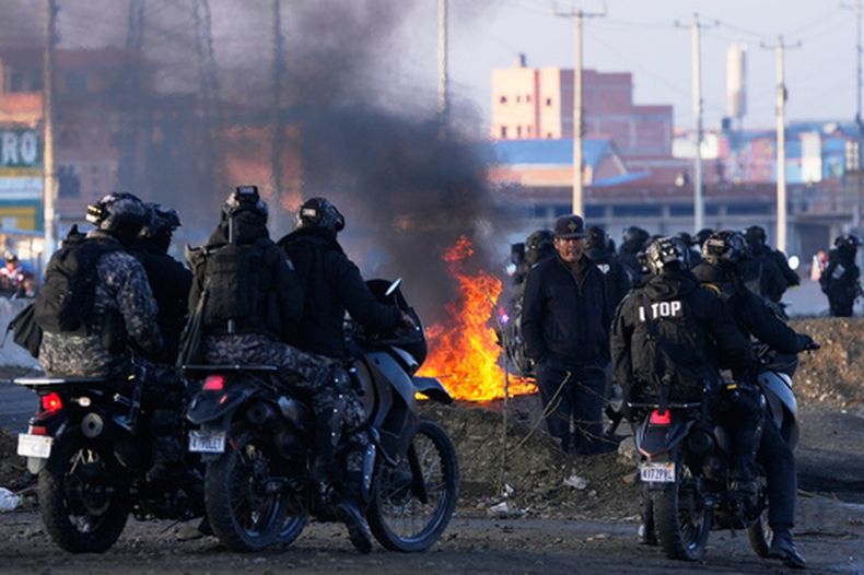 Motociclistas aguardan cerca de las barricadas levantadas por manifestantes antigubernamentales en una carretera, el sábado 23 de mayo de 2026, en El Alto, Bolivia. (AP Foto/Juan Karita)