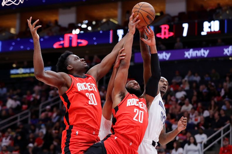 Clint Capela (30) y Josh Okogie (20), de los Rockets de Houston, disputan un rebote con Dariq Whitehead, derecha, de los Grizzlies de Memphis, durante la primera mitad del juego de baloncesto de la NBA, el domingo 12 de abril de 2026, en Houston. (AP Foto/Michael Wyke)