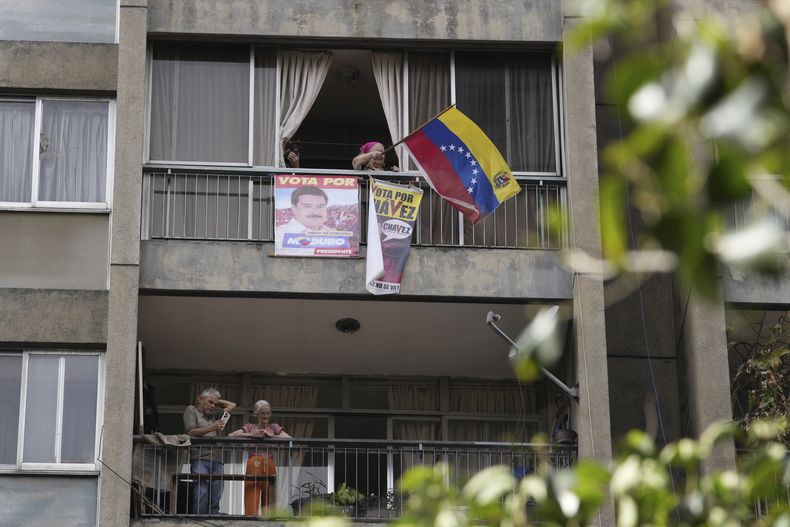 Una simpatizante del presidente Nicolás Maduro ondea una bandera nacional desde su balcón mientras sus seguidores se reúnen para un mitin del gobierno en Caracas, Venezuela, el sábado 3 de agosto de 2024. (Foto AP/Matías Delacroix)